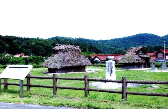 藁ぶき屋根の小屋や石碑がいくつかある国秀遺跡の写真