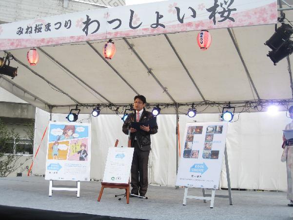みね桜まつりの舞台上で3枚のパネルに囲まれて「美祢市COOL CHOICE宣言」をしている市長の写真