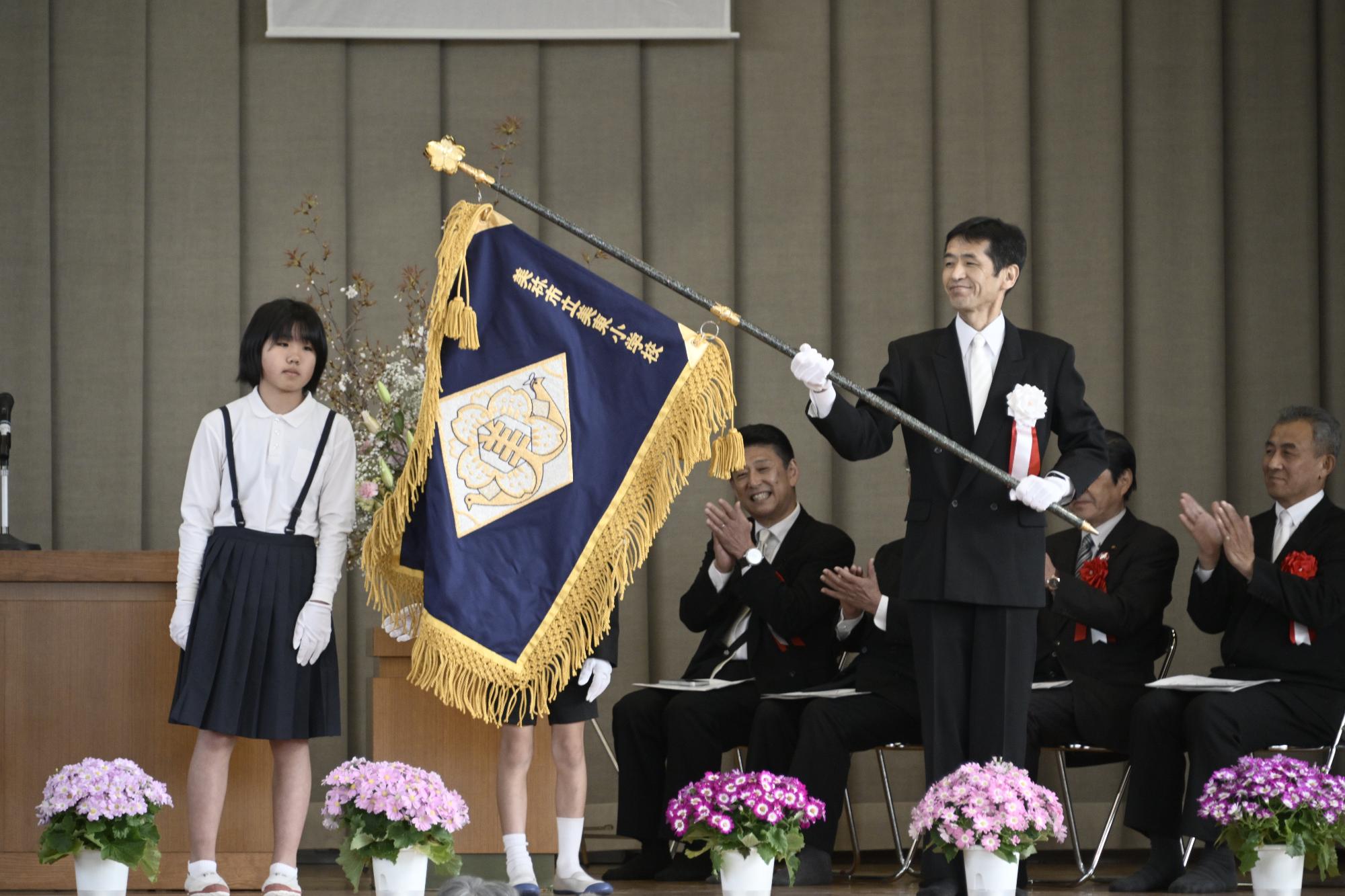 美東小学校の校旗が児童により取り付けられ歌田校長が掲げました。