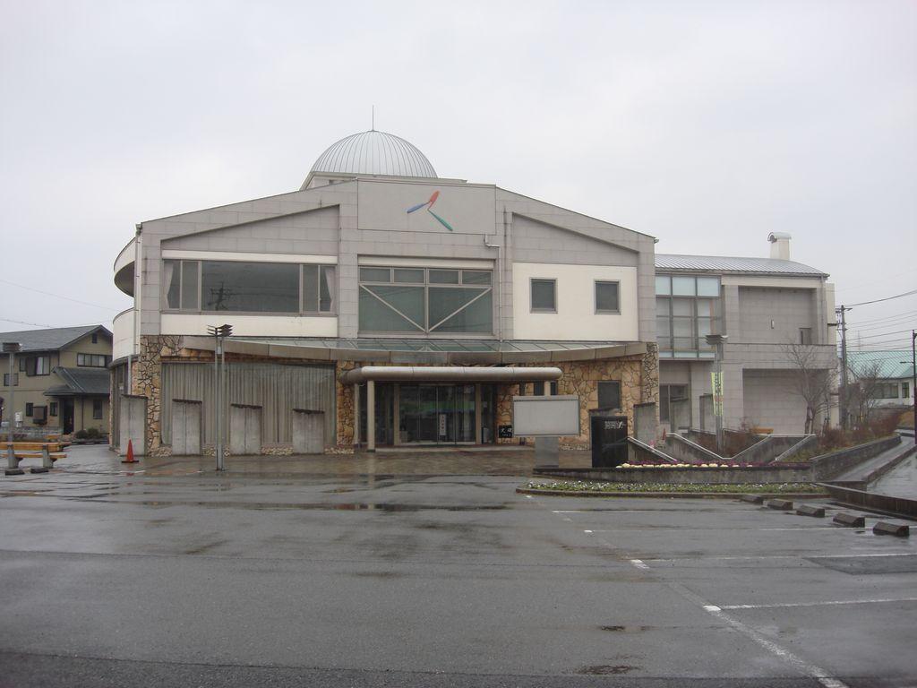 白とグレーの外壁の2階建てで、2階に大きな窓がある美祢来福センターの外観写真
