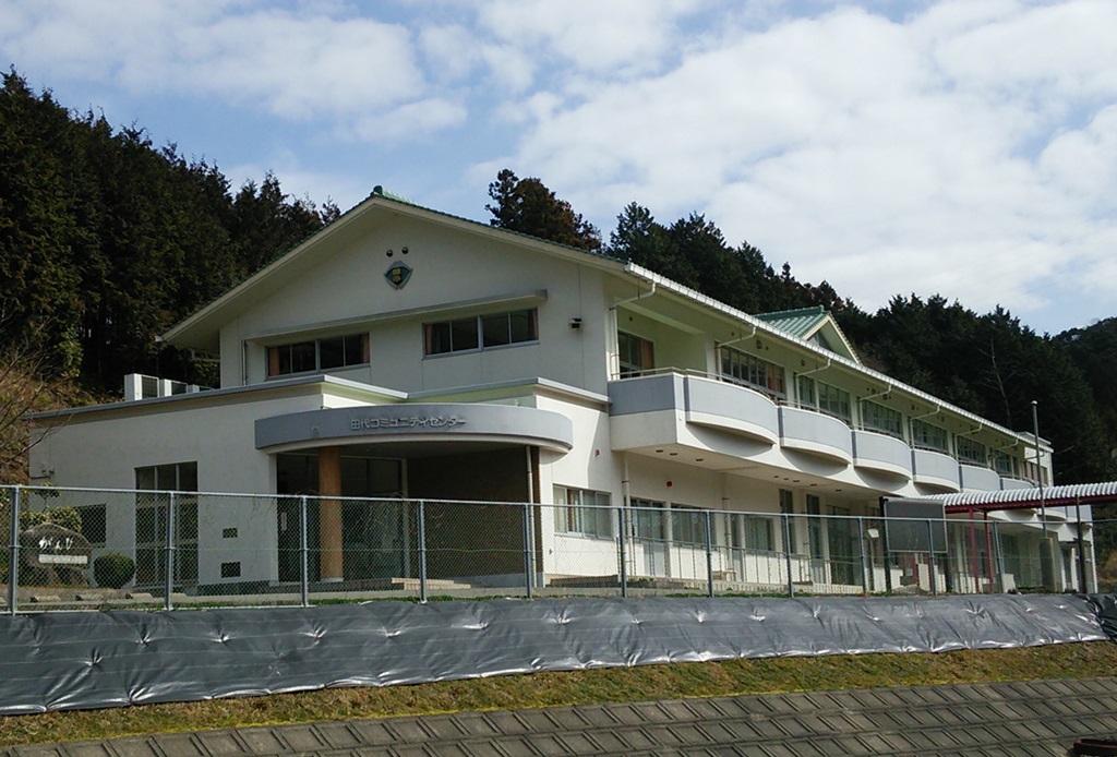 白い外壁で2階建て、2階にはベランダがついている田代コミュニティセンターの建物の外観写真