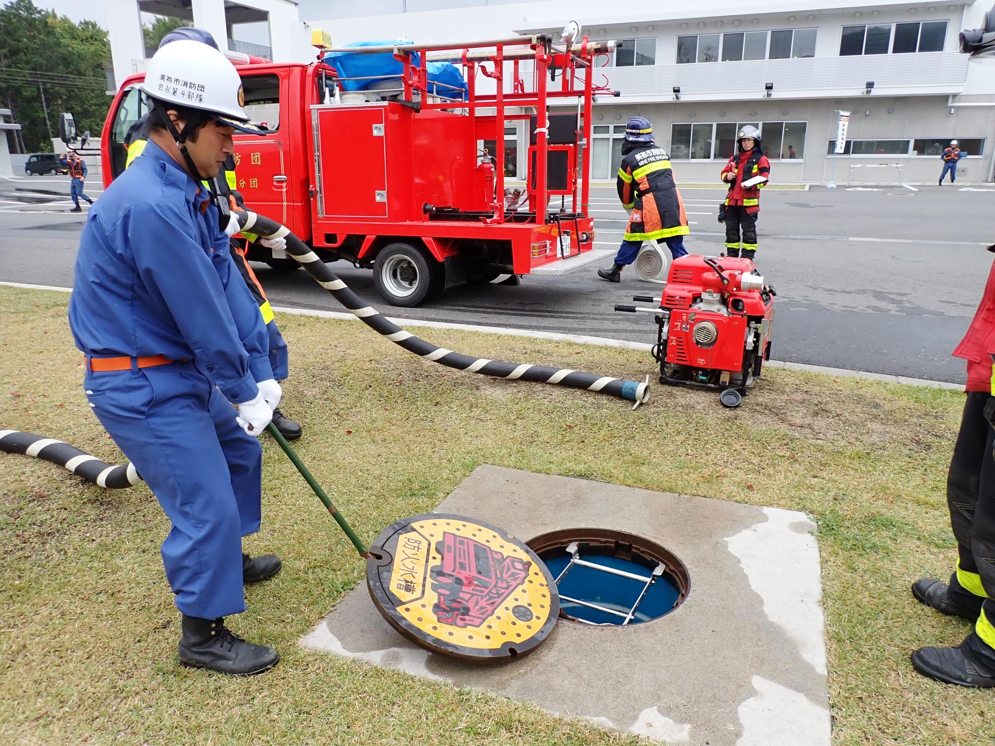 防火水槽の蓋を開ける消防団員