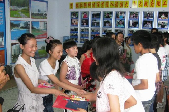 現地の生徒達と市内の中学生達が向かい合って並び握手をしてプレゼント交換をしている写真