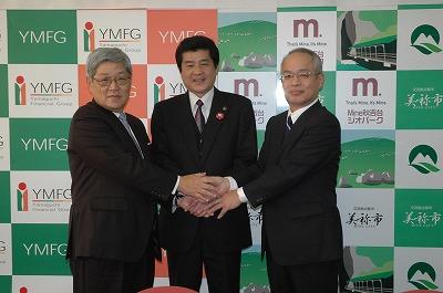 美祢市市長と株式会社山口銀行、株式会社YMFG ZONEプラニングの関係者の方々が互いに握手している写真