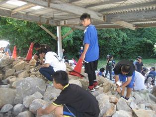 ごつごつと石が積まれている場所で化石採集をしている子供たちの写真