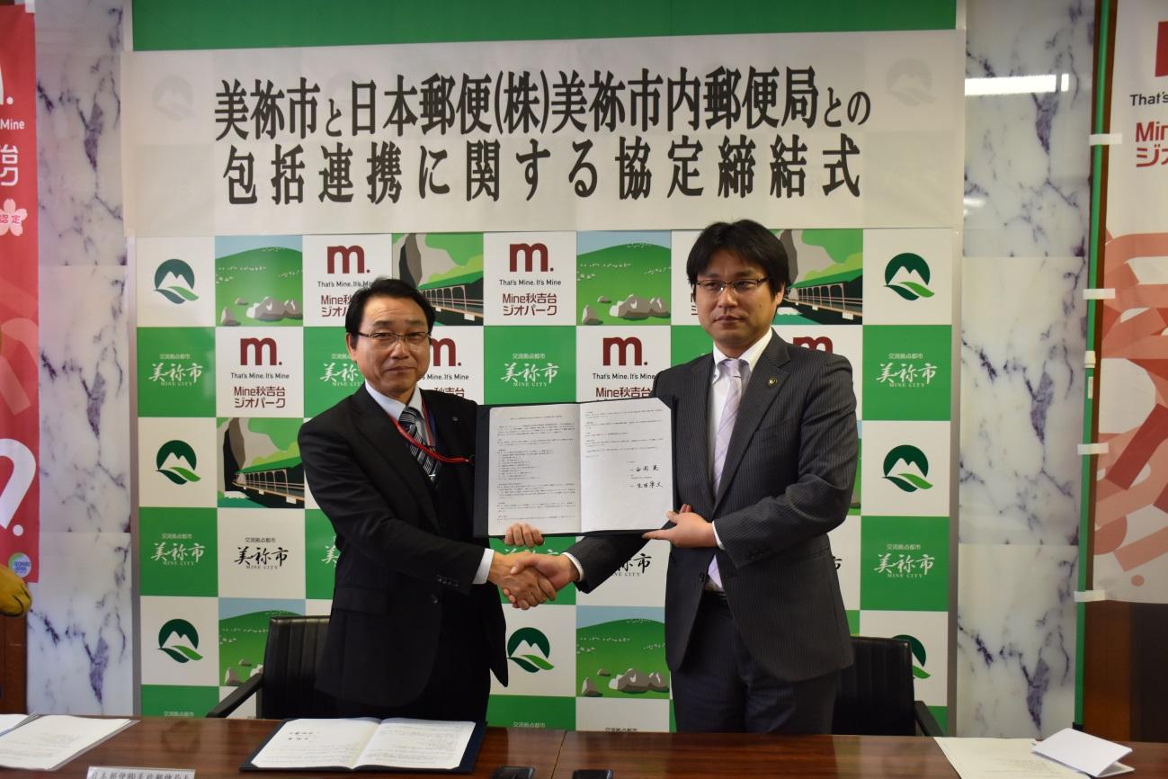 日本郵便株式会社美祢市内郵便局の方と市長が一緒に協定書を持ちながら握手を交わしている写真